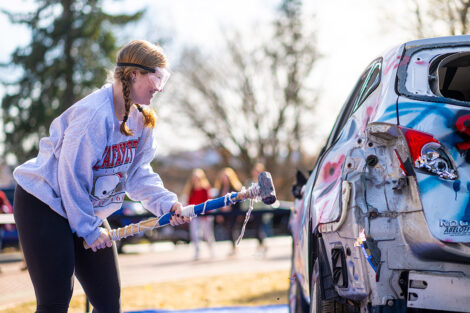 A student uses a sledgehammer on the Lehigh car.