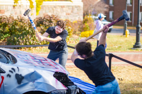 A student uses a sledgehammer on the Lehigh car.