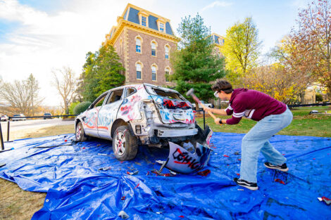 A student uses a sledgehammer on the Lehigh car.