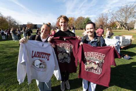 Students smile, holding tshirts.