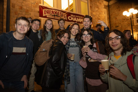 Students stand and smile with hot chocolate.