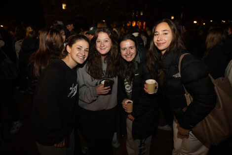 Students stand and smile with hot chocolate.