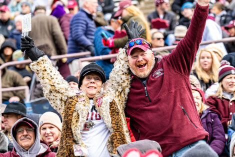 Two alumni in the crowd cheer, standing up!