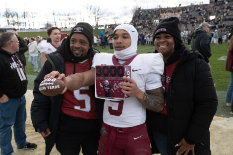 A football player holds a sign with their family.