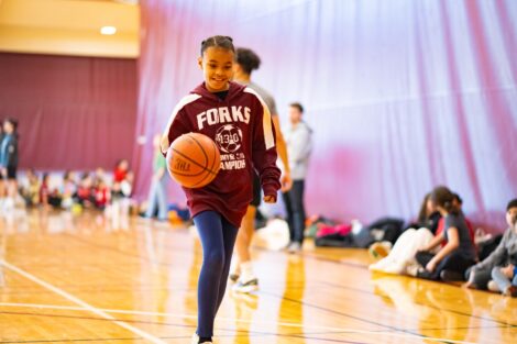 A young girl dribbles a basketball during School Day Game.