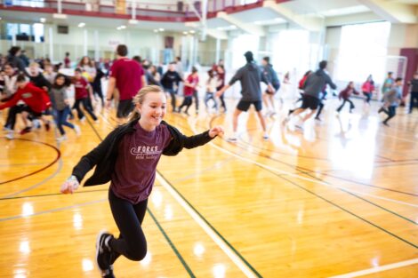 A girl runs across the basketball court during School Day Game.