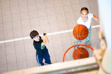 Two students shoot baskets into a hoop.