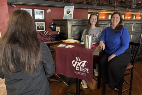 Becca Pichetto and Abbie Steinly sit behind a table at 3rd & Ferry Fish Market, greeting Lafayette employees as they checked in to Shop Local Day.