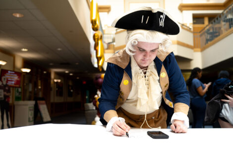 A student dressed as the Marquis signs a banner.