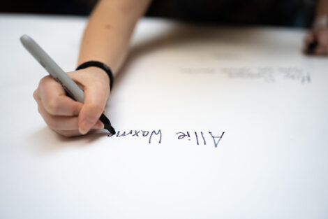 Close up image of a student signing a banner.