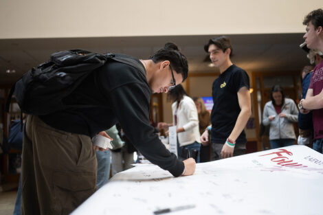 A student signs a banner.