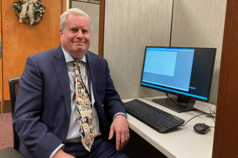 Mark L. Goldstone smiles beside his computer