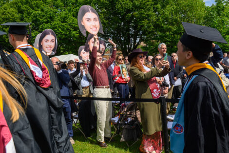 Families hold up photos of their graduates