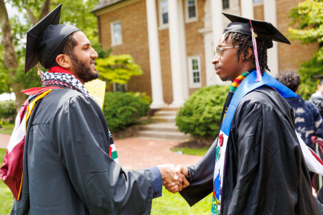 Two graduates shake hands.