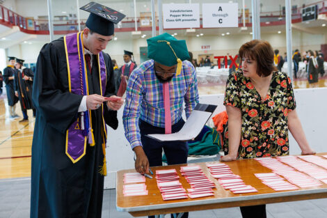 Staff members help a graduate find their card.