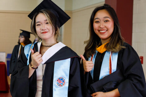 Students put on their caps and gowns with the help of fellow students and staff.