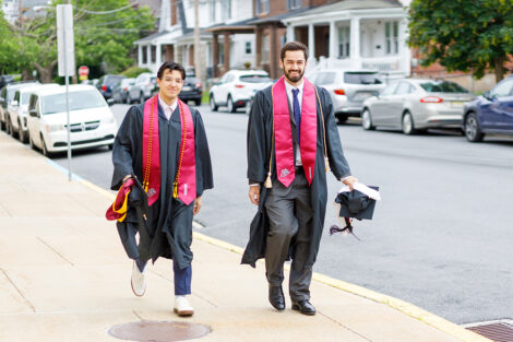 Students in graduation gowns walk up McCartney.