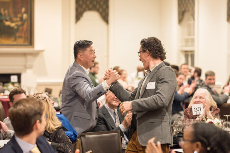 Two faculty members shake hands at the Faculty Staff Awards