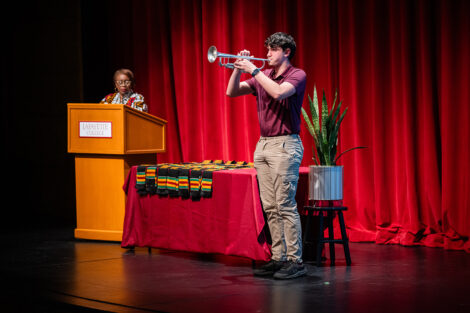 A student plays a trumpet at the Donning of the Kente