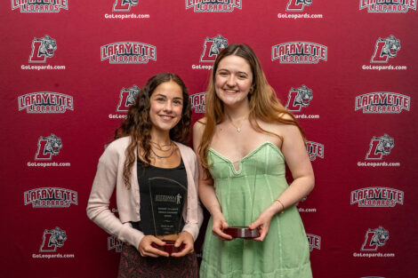 Milan Iezzi and Lauren Finlay are standing and holding glass awards.