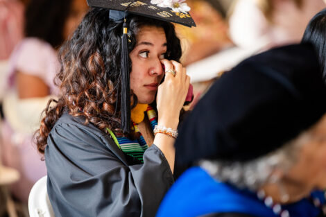 A graduate wipes a tear from their eye