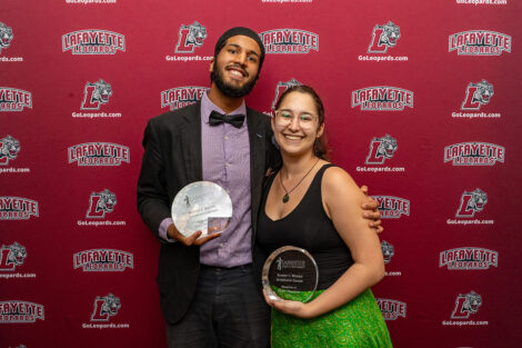 Yaseen Saleh ’25 and Elise Trocker ’26 are holding glass awards.
