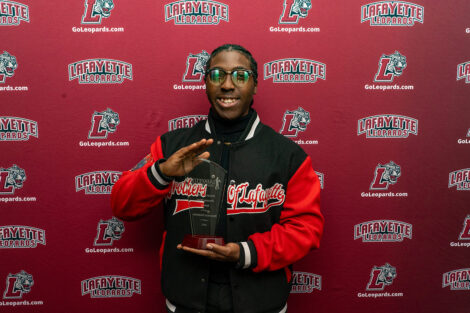 Brandon Harding '26 is holding a glass award.