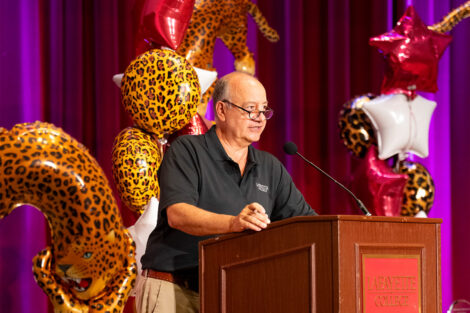 Board of Trustees, Robert E. Sell ’84, H’18 is standing at a podium. Leopard balloons are in the background.