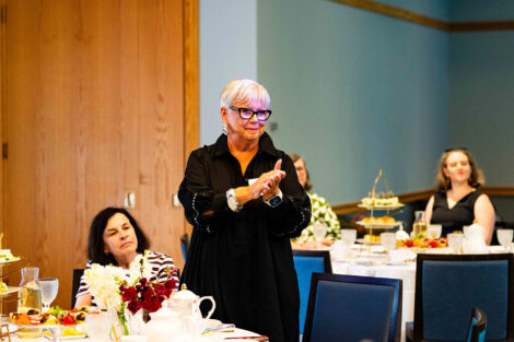 A woman stands and is clapping.