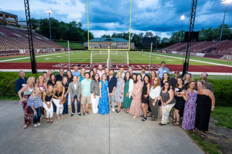 A large group of alumni stand at the goal post at Fisher Field.