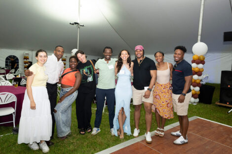 A group of nine alumni are smiling at the camera