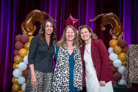Fran Della Badia '91, Kathleen Squires '88, and Nicole Farmer Hurd are standing arm in arm and smiling at the camera.