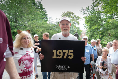 A member of the Class of 1975 is holding a sign that reads 1975.