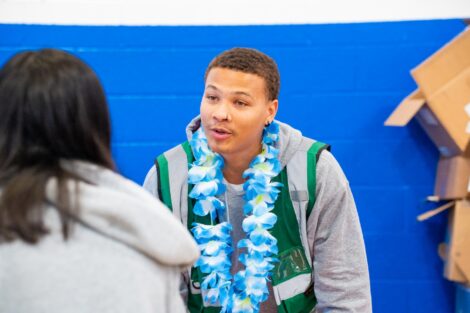A Lafayette volunteer wearing a green vest talks with a customer