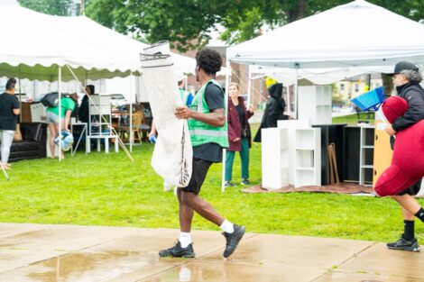 A Lafayette volunteer in a green vest carries an item out of the West Ward Sale