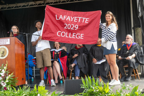 Shiloh Hay '29 and Addison Ford '29 hold the class flag on stage during Convocation.