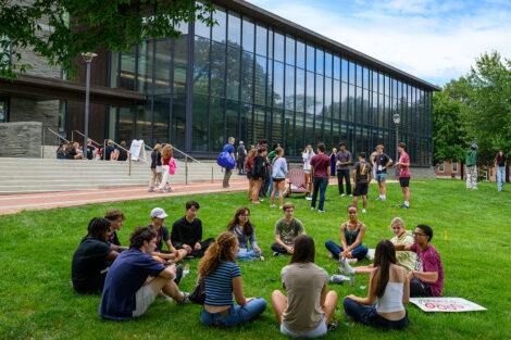 Students sit in a circle on the grass of Lafayette College's Quad, in front of Skillman Library.