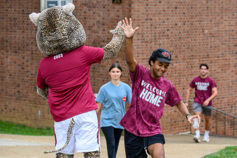 A student high fives Roary, Lafayette College's mascot.