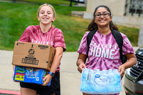 Two students carry boxes and water bottles into a residence hall at Lafayette College.