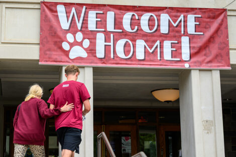 A Welcome Home sign hangs on Farinon College Center, as a student and family member walk into the building