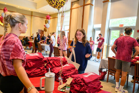A student picks up their tshirt from a large table.