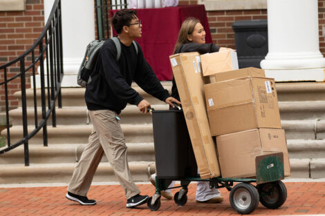Students wheel cardboard boxes across campus.