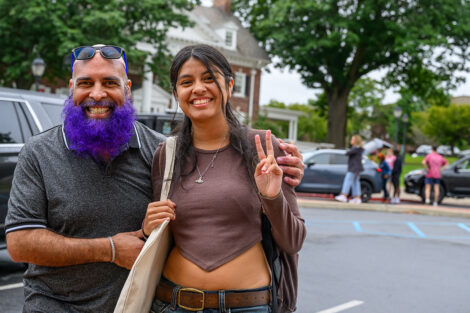 A student smiles with their family member, giving the peace sign.