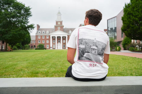 A student in a Bicentennial Abercrombie & Fitch tshirt looks at Watson Hall