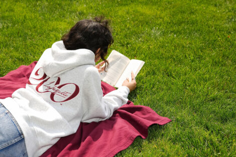 A student reads a book on the Quad