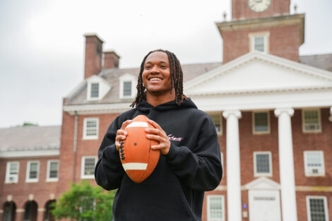 A student throws a football while wearing Abercrombie and Fitch gear.