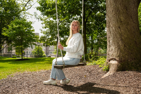 A student smiles on a swing, wearing Bicentennial Abercrombie & Fitch clothing