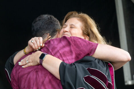 President Nicole Hurd hugs a student on stage during Convocation