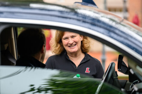 President Nicole Hurd smile as a parent arrives in their vehicle.