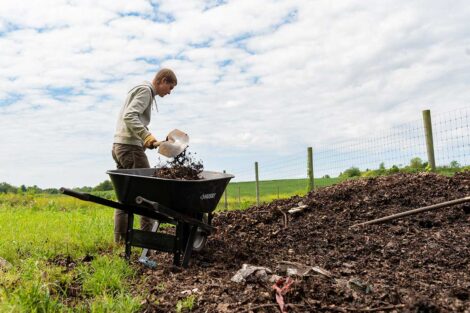 POSP student filling up a wheelbarrow with dirt on LaFarm